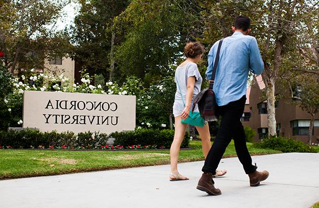 two students walking past a Concordia University sign